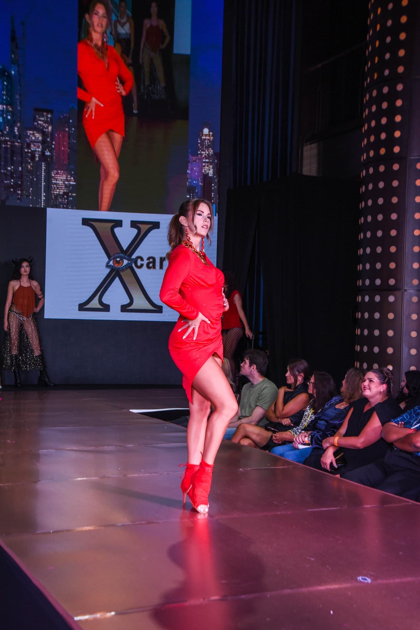 Molly Hagman full-length in red with Xcarii logo behind her at NYFW Fall 2024